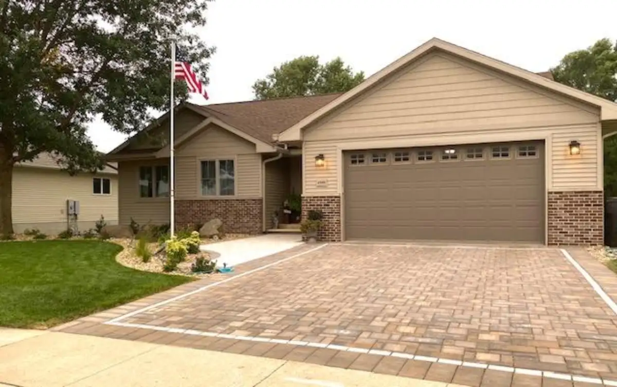 Ranch home with tan paver driveway and landscaping